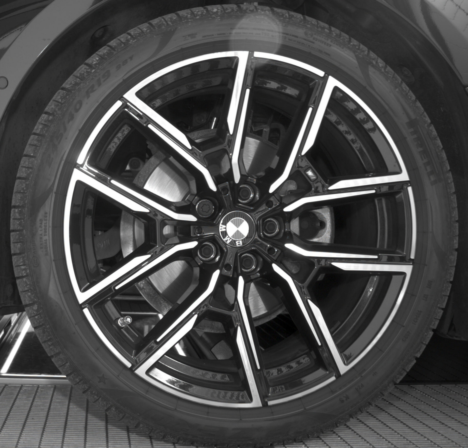 BMW alloy wheel photographed at a vehicle site entrance.