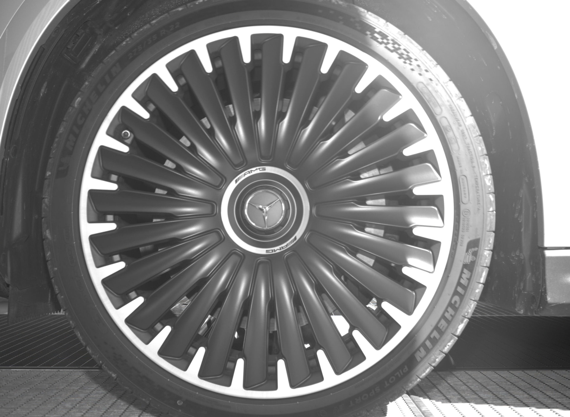 Mercedes-AMG wheel photographed at a vehicle site entrance.