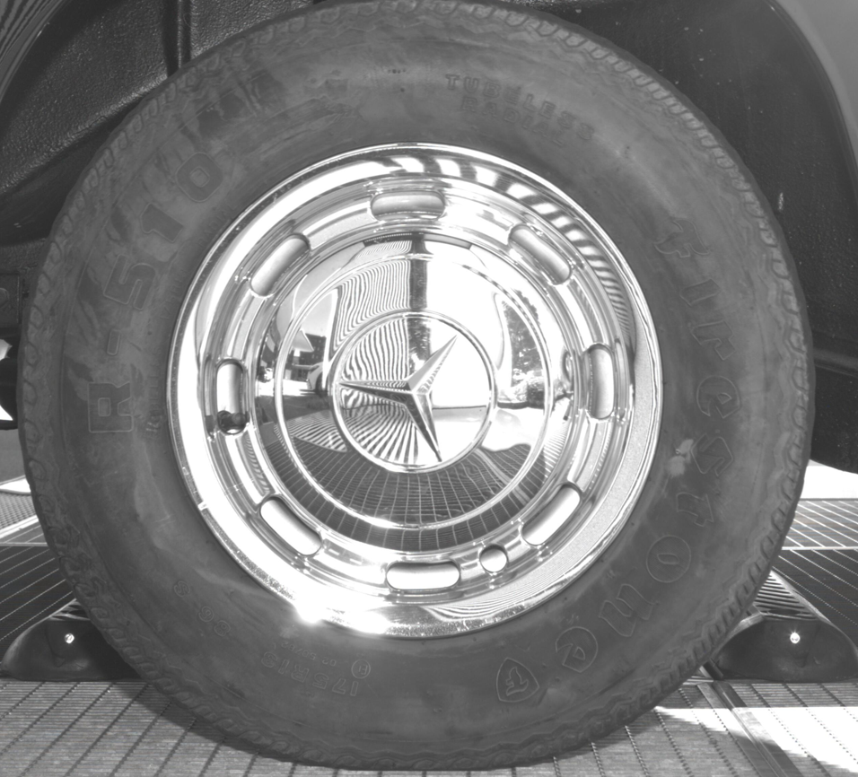 Classic Mercedes wheel photographed at a vehicle site entrance.